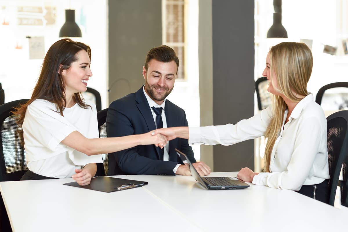 Three people smiling when signing third-party insurance policy