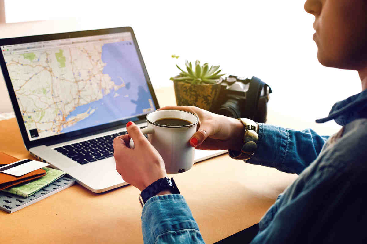 Stylish Girl Holding Coffee On Background Of Laptop Using Software