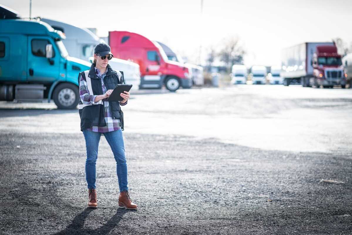 Woman standing in front of trucks and checking a shipping order